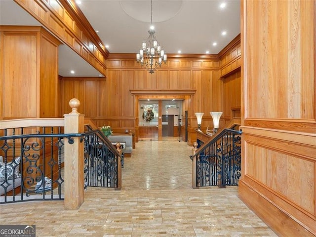 hall featuring ornamental molding, a notable chandelier, and wooden walls