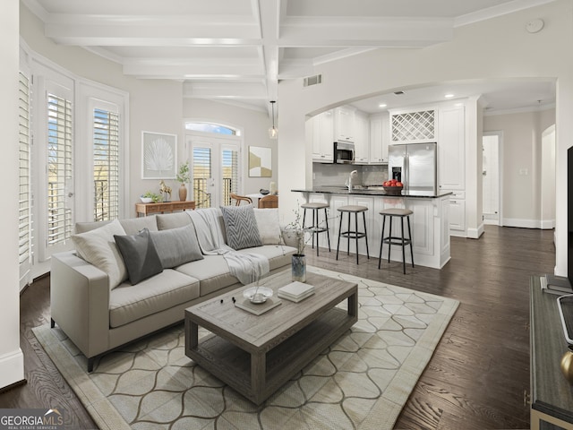 living room featuring dark hardwood / wood-style flooring, sink, ornamental molding, and beamed ceiling