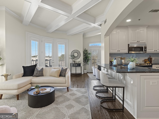 living room with dark hardwood / wood-style floors, sink, ornamental molding, coffered ceiling, and beam ceiling