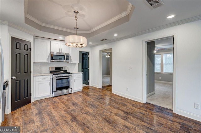 kitchen with pendant lighting, white cabinetry, stainless steel appliances, and a tray ceiling