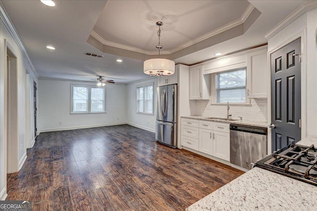 kitchen featuring a tray ceiling, light stone counters, white cabinets, and appliances with stainless steel finishes