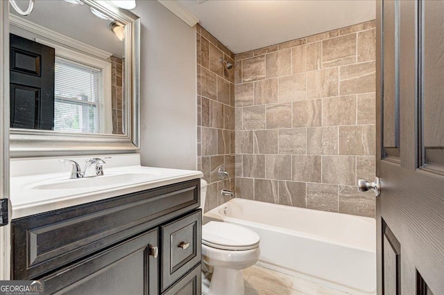 full bathroom featuring toilet, vanity, tiled shower / bath combo, and ornamental molding