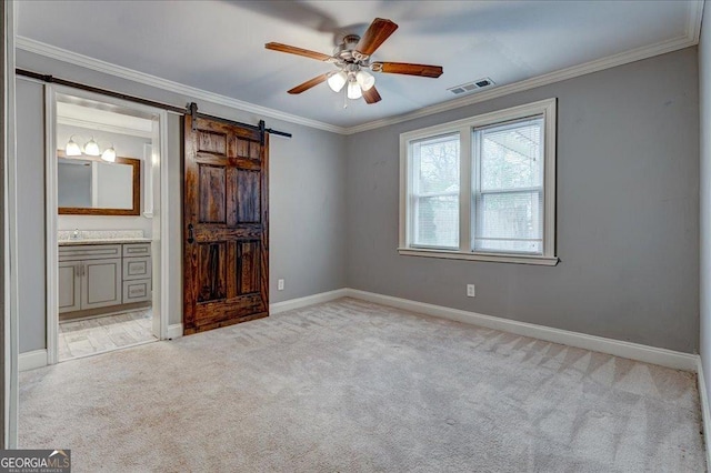 carpeted empty room featuring a barn door, ceiling fan, and ornamental molding