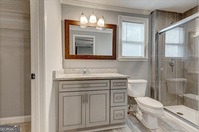 bathroom featuring vanity, toilet, a shower with shower door, and ornamental molding