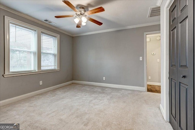 carpeted spare room with ceiling fan and ornamental molding