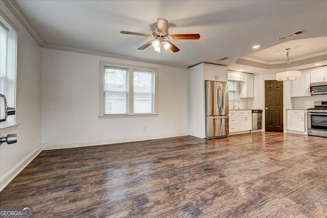 unfurnished living room with a tray ceiling, ceiling fan, sink, and ornamental molding