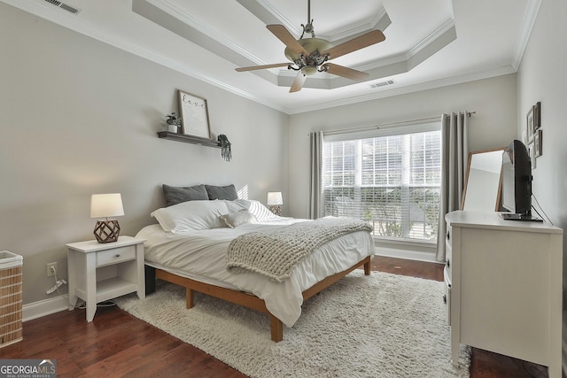 bedroom featuring dark hardwood / wood-style flooring, a raised ceiling, ceiling fan, and crown molding