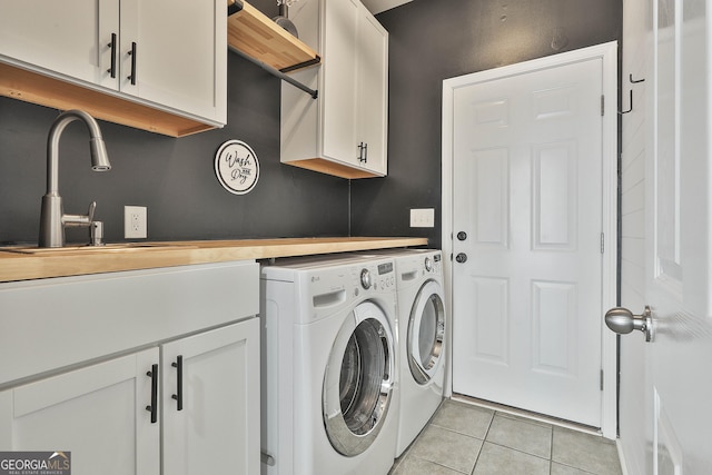 washroom featuring washing machine and clothes dryer, sink, light tile patterned flooring, and cabinets