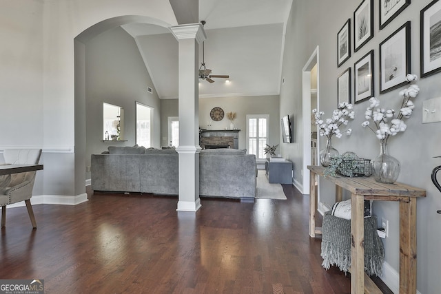 living room with a stone fireplace, ceiling fan, ornate columns, and dark hardwood / wood-style floors