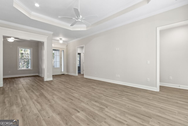 unfurnished living room featuring crown molding, baseboards, light wood-type flooring, a raised ceiling, and a ceiling fan