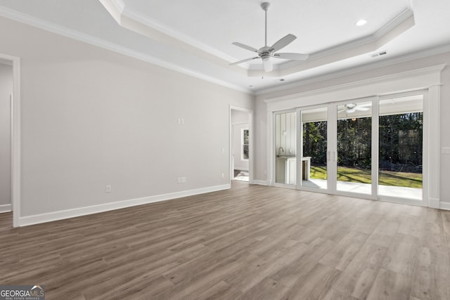 unfurnished living room with a ceiling fan, a raised ceiling, wood finished floors, and ornamental molding