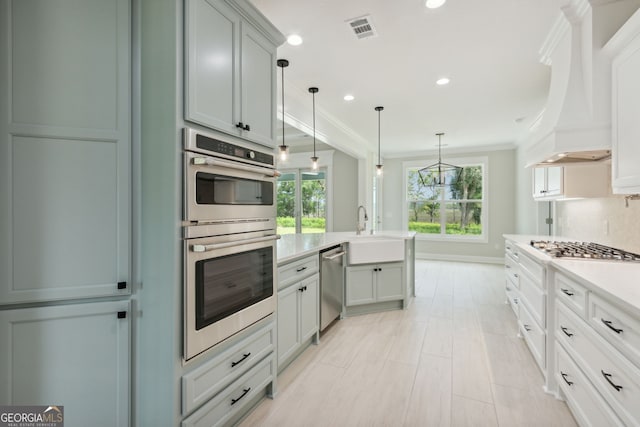 kitchen featuring premium range hood, sink, appliances with stainless steel finishes, pendant lighting, and backsplash