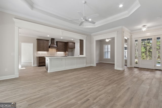 unfurnished living room featuring a raised ceiling, a healthy amount of sunlight, and a ceiling fan