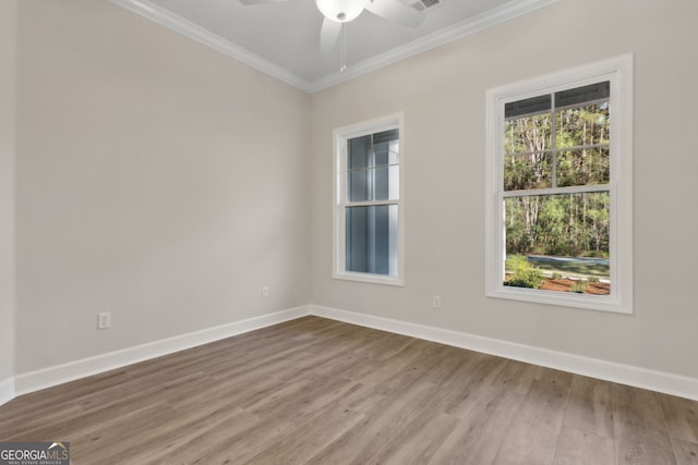 empty room with crown molding, wood finished floors, baseboards, and ceiling fan