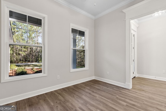 spare room with ornamental molding, baseboards, and wood finished floors