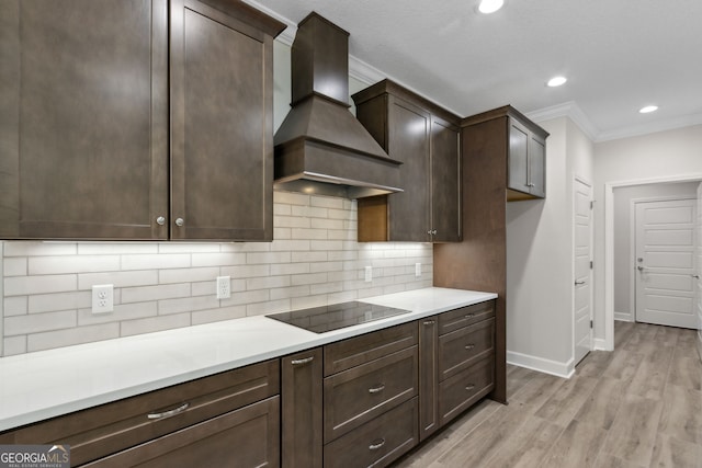 kitchen featuring ornamental molding, decorative backsplash, dark brown cabinetry, black electric cooktop, and custom exhaust hood