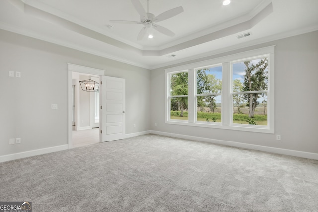 unfurnished room with a tray ceiling, ceiling fan with notable chandelier, ornamental molding, and light colored carpet