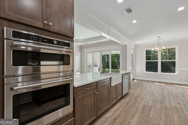 kitchen with visible vents, crown molding, light countertops, stainless steel appliances, and a sink