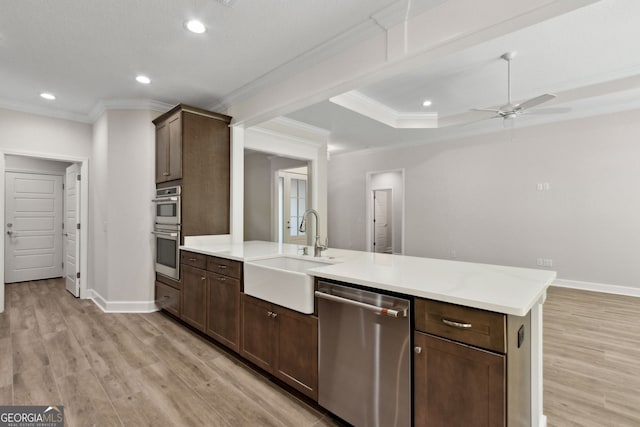 kitchen featuring light wood-style flooring, a sink, a peninsula, appliances with stainless steel finishes, and light countertops