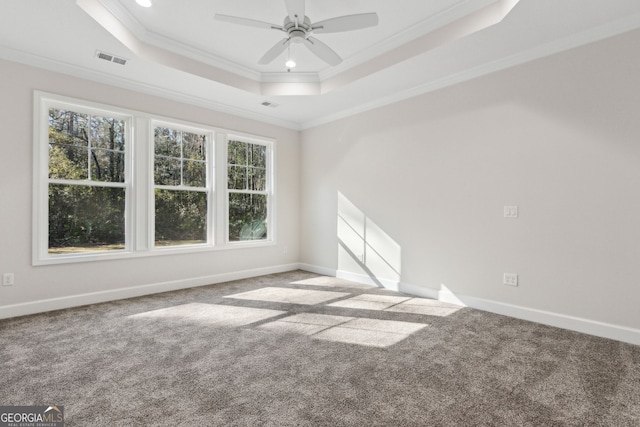 spare room with carpet, visible vents, baseboards, crown molding, and a raised ceiling