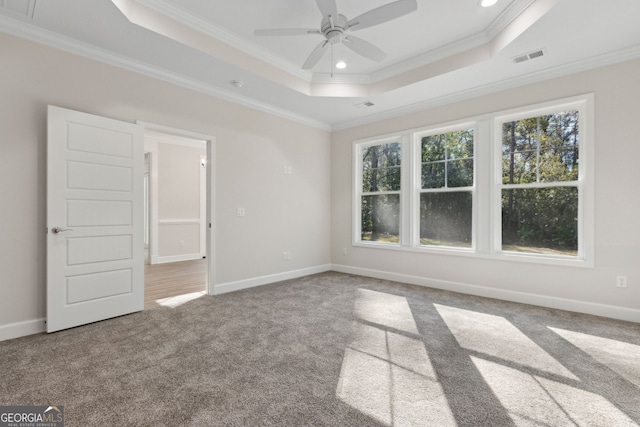 carpeted empty room featuring a tray ceiling, baseboards, and ornamental molding