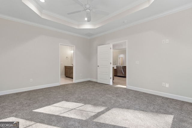 unfurnished bedroom with carpet, baseboards, ensuite bath, ornamental molding, and a raised ceiling