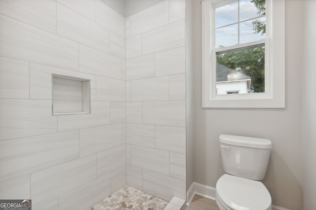 bathroom with toilet and a tile shower