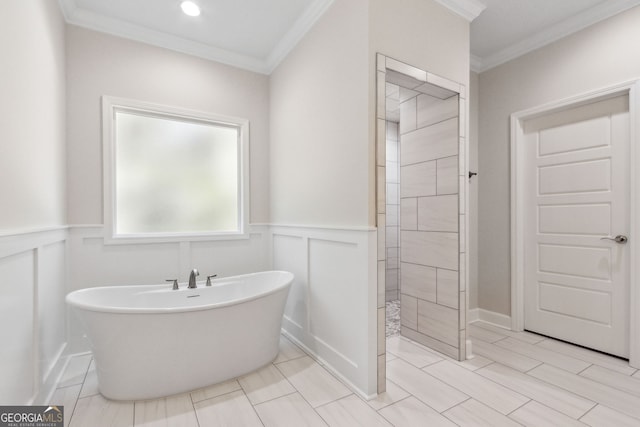 bathroom with ornamental molding, a wainscoted wall, a tile shower, and a freestanding bath