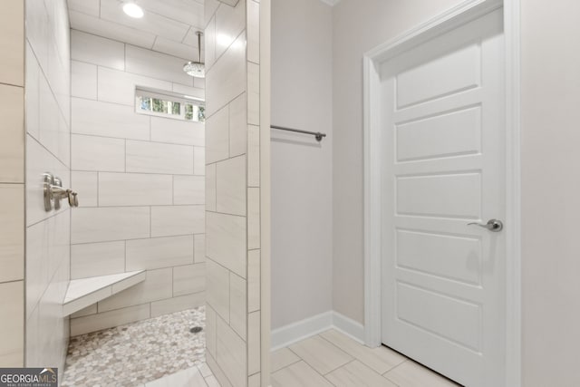 full bath with baseboards and tiled shower