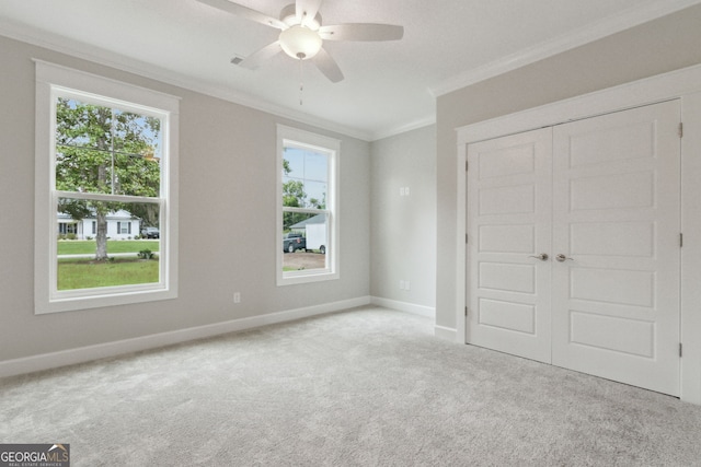 unfurnished bedroom featuring light carpet, crown molding, a closet, and ceiling fan