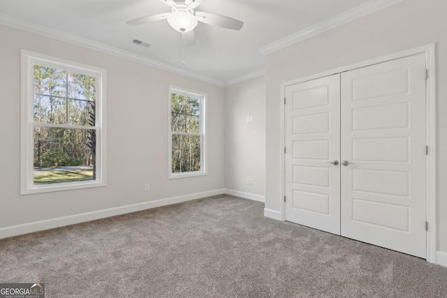 unfurnished bedroom featuring visible vents, baseboards, a closet, crown molding, and carpet flooring