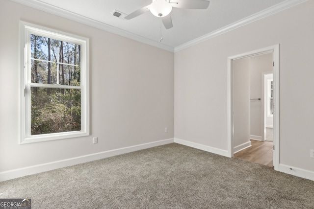 spare room featuring crown molding, carpet, visible vents, and a wealth of natural light