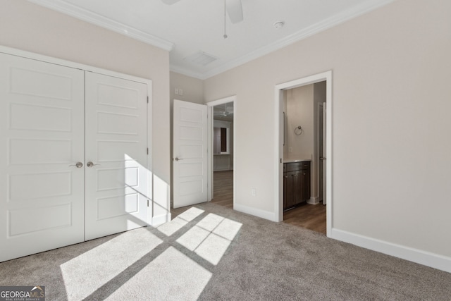 unfurnished bedroom with ornamental molding, ensuite bath, a closet, carpet floors, and baseboards