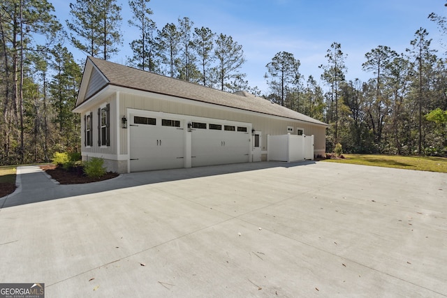 view of property exterior featuring a garage, driveway, and a shingled roof