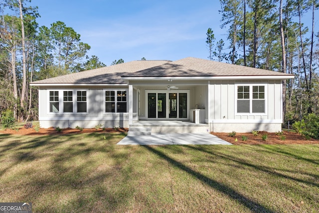 rear view of house with a yard, board and batten siding, ceiling fan, and a shingled roof