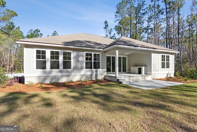 back of property featuring a yard, a patio area, board and batten siding, and a shingled roof