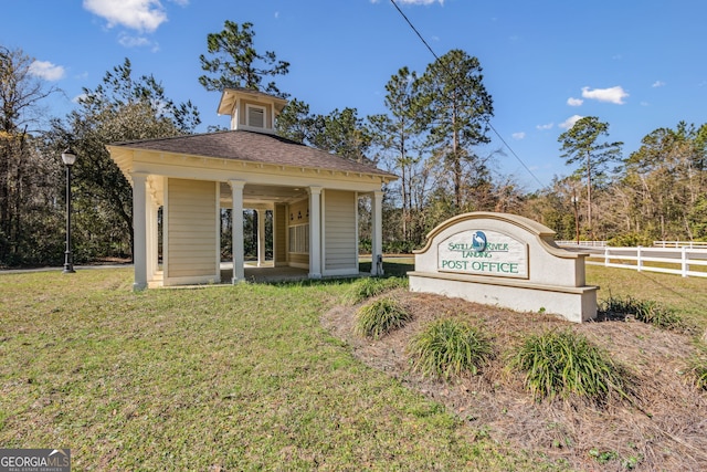 community sign with fence and a lawn