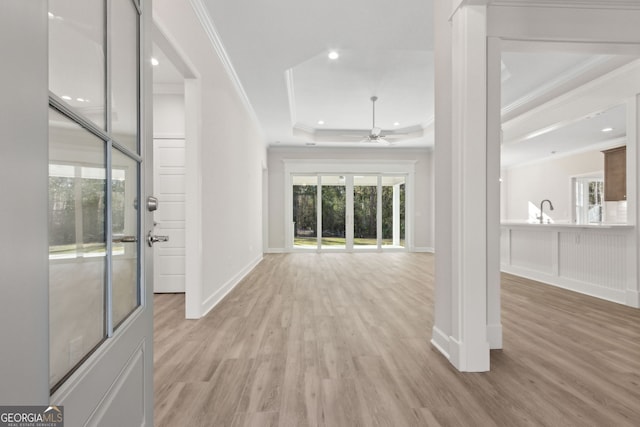 hall featuring light wood finished floors, recessed lighting, a raised ceiling, and ornamental molding