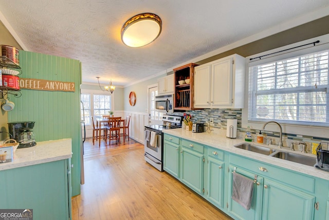 kitchen featuring appliances with stainless steel finishes, crown molding, sink, light hardwood / wood-style flooring, and a notable chandelier