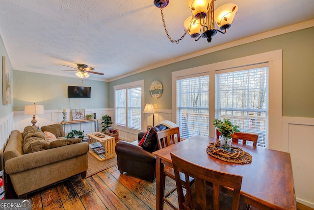 dining space with a textured ceiling, crown molding, wood-type flooring, and ceiling fan with notable chandelier