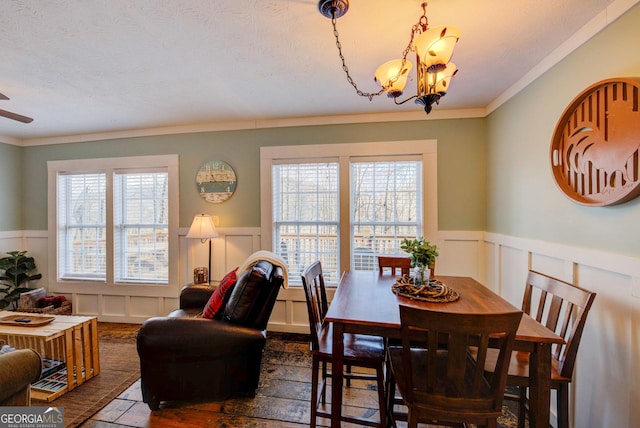 dining space featuring a textured ceiling, crown molding, and ceiling fan with notable chandelier