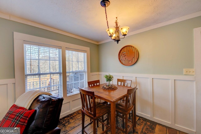 dining room with dark hardwood / wood-style floors, ornamental molding, a textured ceiling, and a chandelier