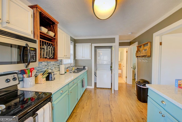 kitchen with decorative backsplash, sink, white cabinetry, black / electric stove, and stacked washer / drying machine