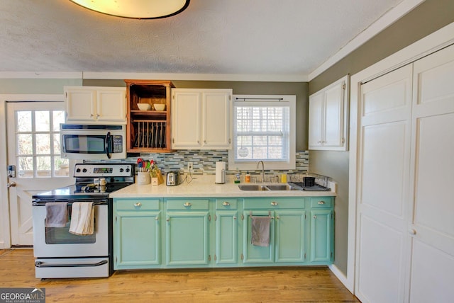 kitchen featuring decorative backsplash, white electric range, white cabinetry, and sink