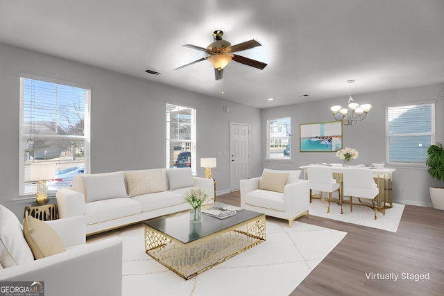 living room with ceiling fan with notable chandelier and hardwood / wood-style flooring