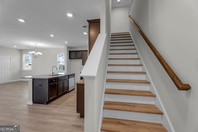 stairs featuring hardwood / wood-style floors, sink, and a chandelier