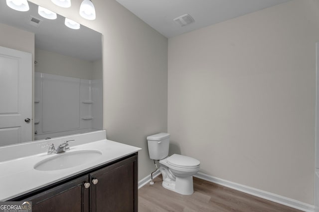 bathroom featuring a shower, vanity, hardwood / wood-style flooring, and toilet