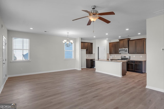 kitchen featuring pendant lighting, backsplash, a kitchen island with sink, appliances with stainless steel finishes, and wood-type flooring