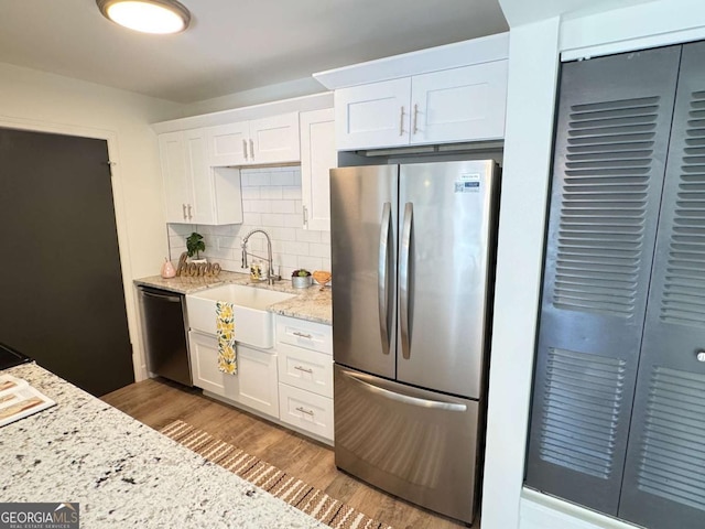 kitchen with light stone countertops, sink, decorative backsplash, white cabinets, and appliances with stainless steel finishes