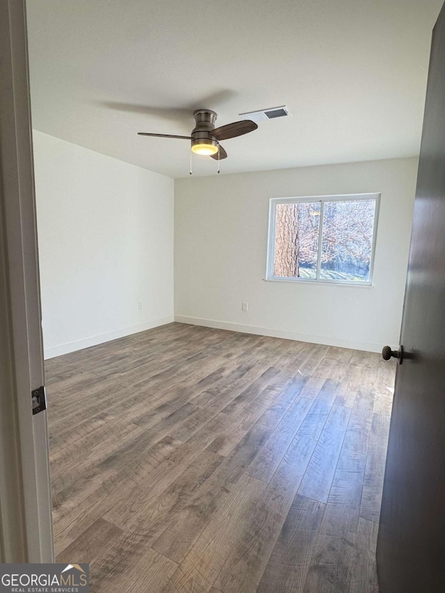 empty room featuring ceiling fan and dark wood-type flooring